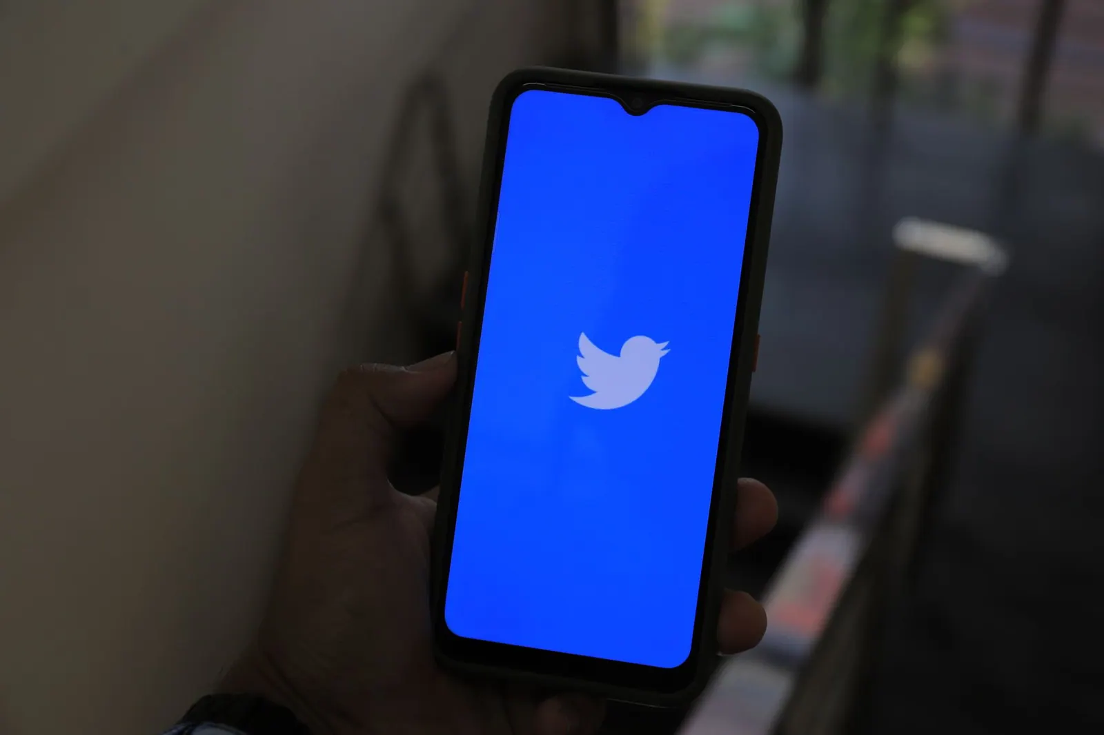 Close-up of a hand holding a smartphone displaying the Twitter app screen. Feature updates comparison: facts, examples and context