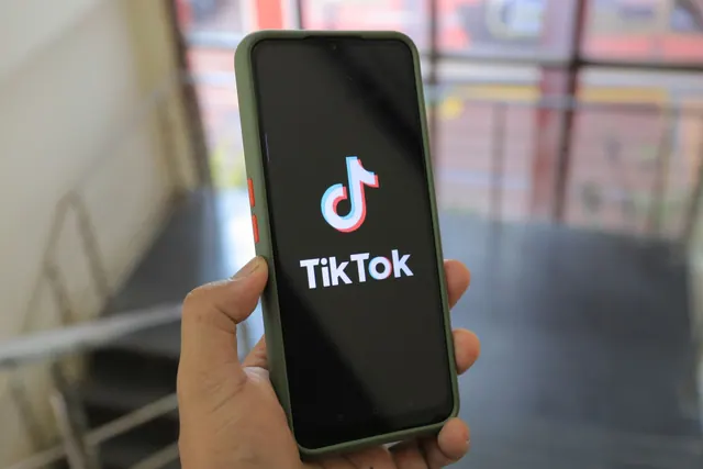 Hand holding a smartphone showing the TikTok app screen in an indoor setting. Platform trends: what beginners should know